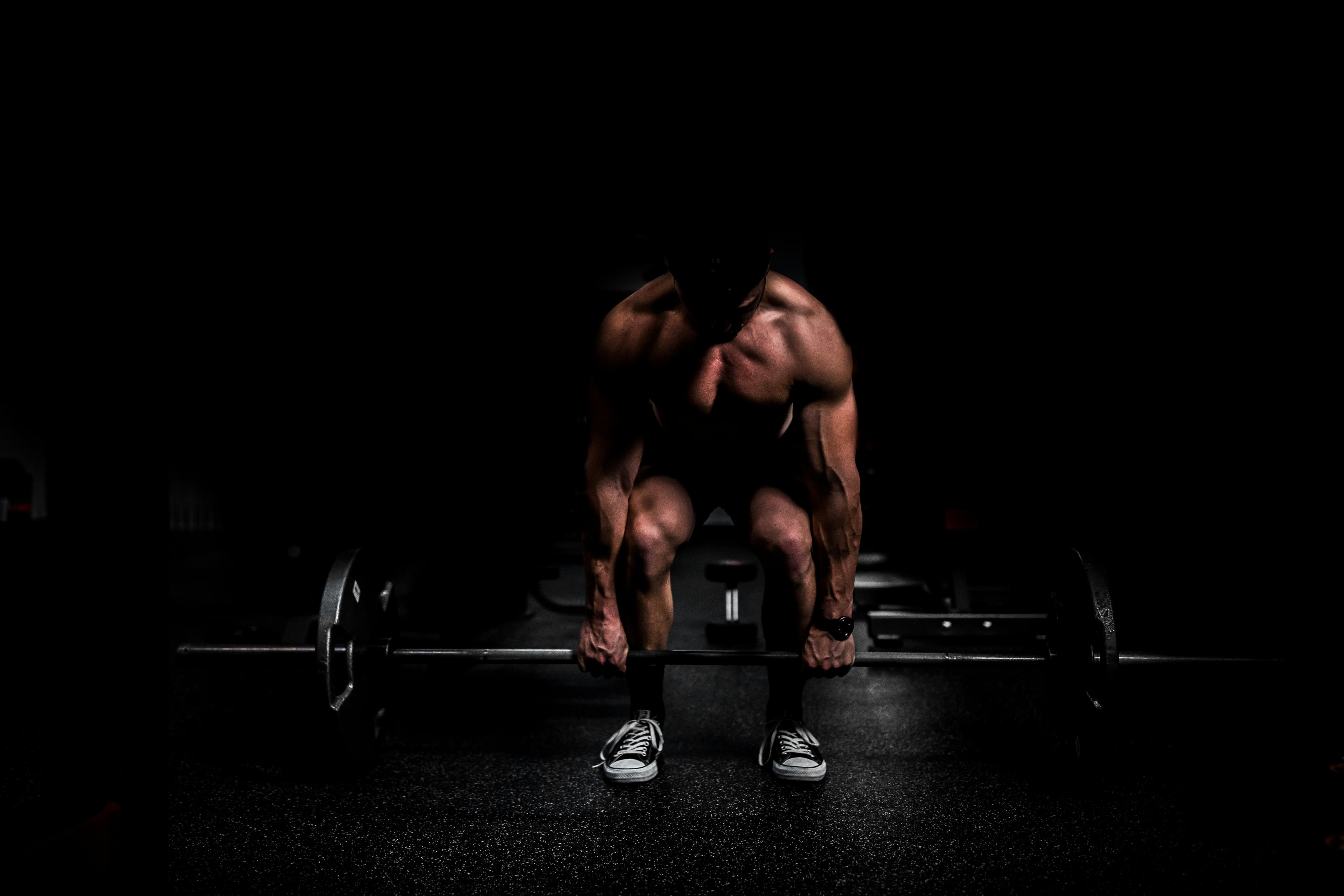 Athlete preparing for a deadlift in a dark, cinematic gym