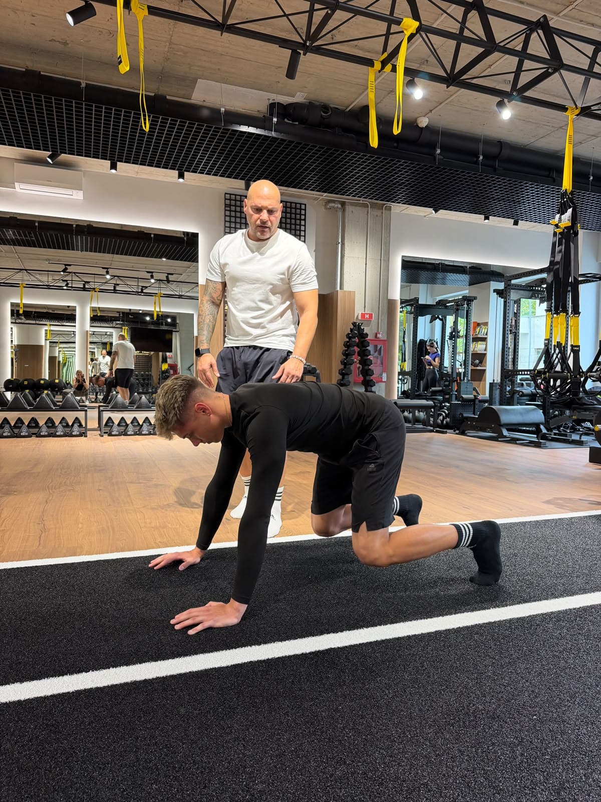 Coach supervising an athlete's mobility drill on the sprint track